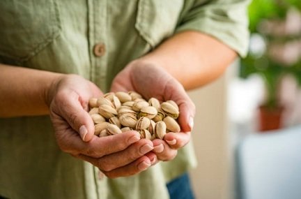 Primer plano de las manos de la mujer sosteniendo el montón de pistacho - Fotografía de stock