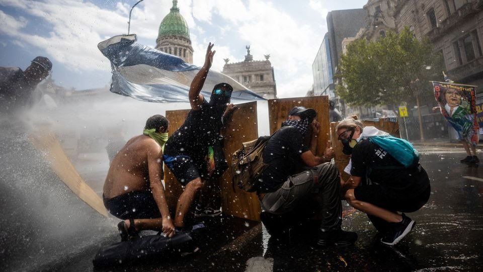 Manifestantes se protegen de un cañón de agua con tablas de madera en medio de enfrentamientos contra la policía durante una protesta convocada por sindicatos de trabajadores contra la reforma laboral. 11 de febrero de 2026, Buenos Aires, Argentina.Tomas Cuesta/Getty Images